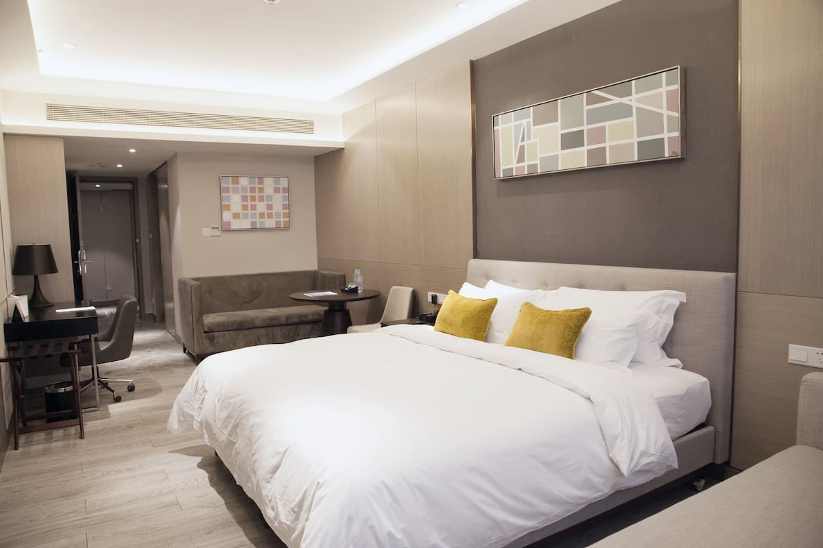 Ein Hotelzimmer mit einem großen Bett, einem Schreibtisch, einem Sessel und einem kleinen Tisch.