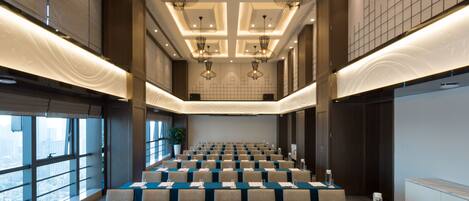 A conference room with rows of tables, large windows, and modern lighting fixtures.