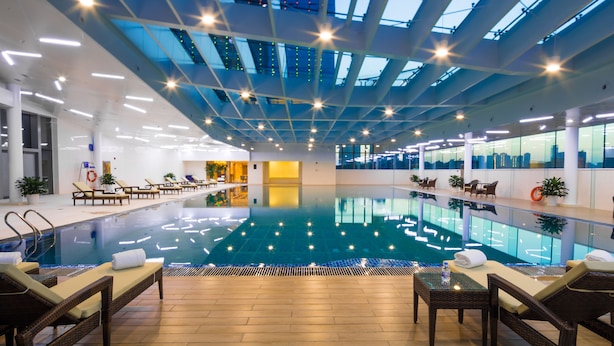 Una piscina interior con sillas de descanso y techo de cristal.
