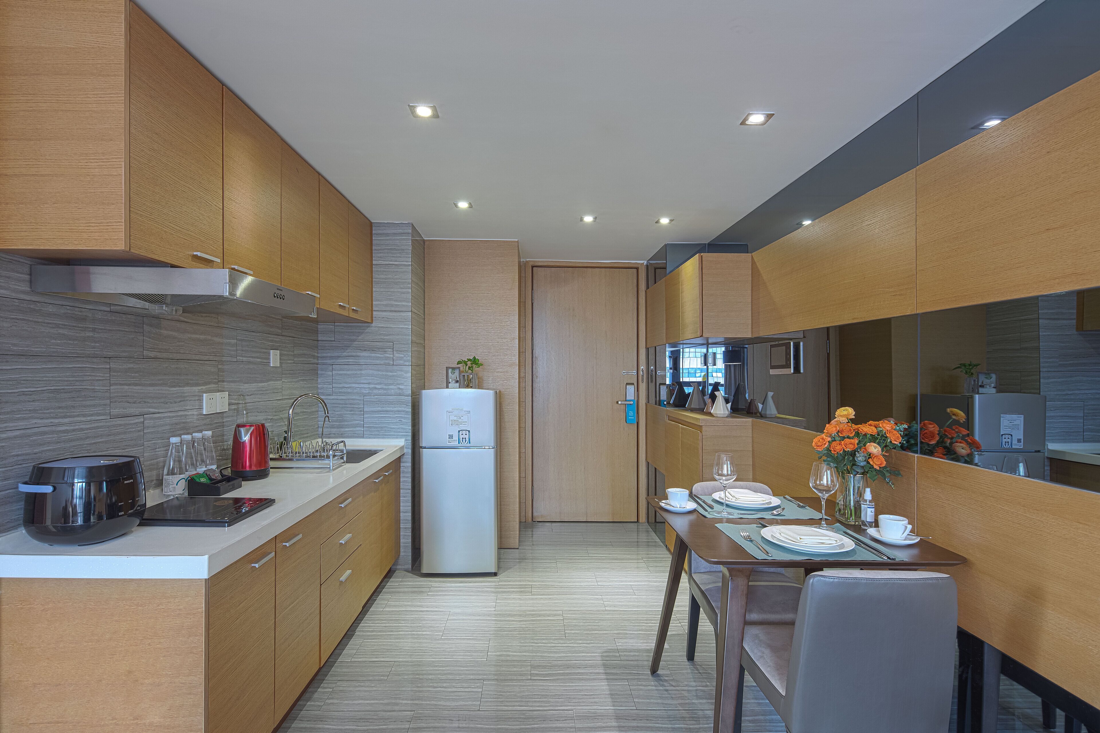 Une cuisine moderne avec des meubles en bois, une hotte de cuisson en acier inoxydable et un réfrigérateur encastré.