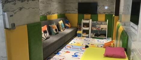 A child-friendly room with a sofa, a bed, and a play area.