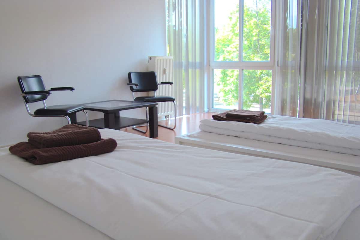 A hotel room with two beds, a desk, and a chair.