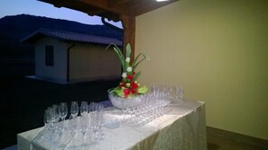Una mesa dispuesta con copas de vino y un centro de mesa floral, con un edificio al fondo.