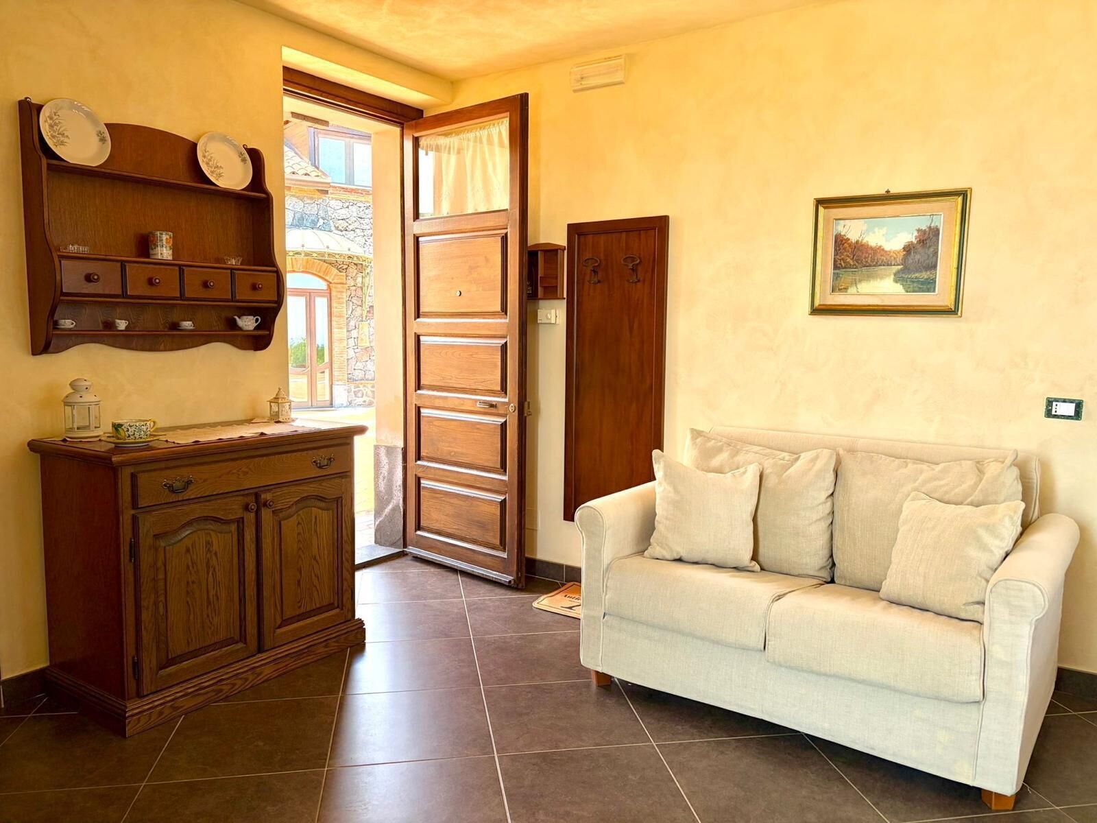 A living room with a sofa, a cabinet, a door, and a painting on the wall.