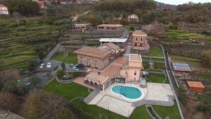 Vista aérea de una extensa propiedad con varias construcciones, una piscina y campos en terrazas.