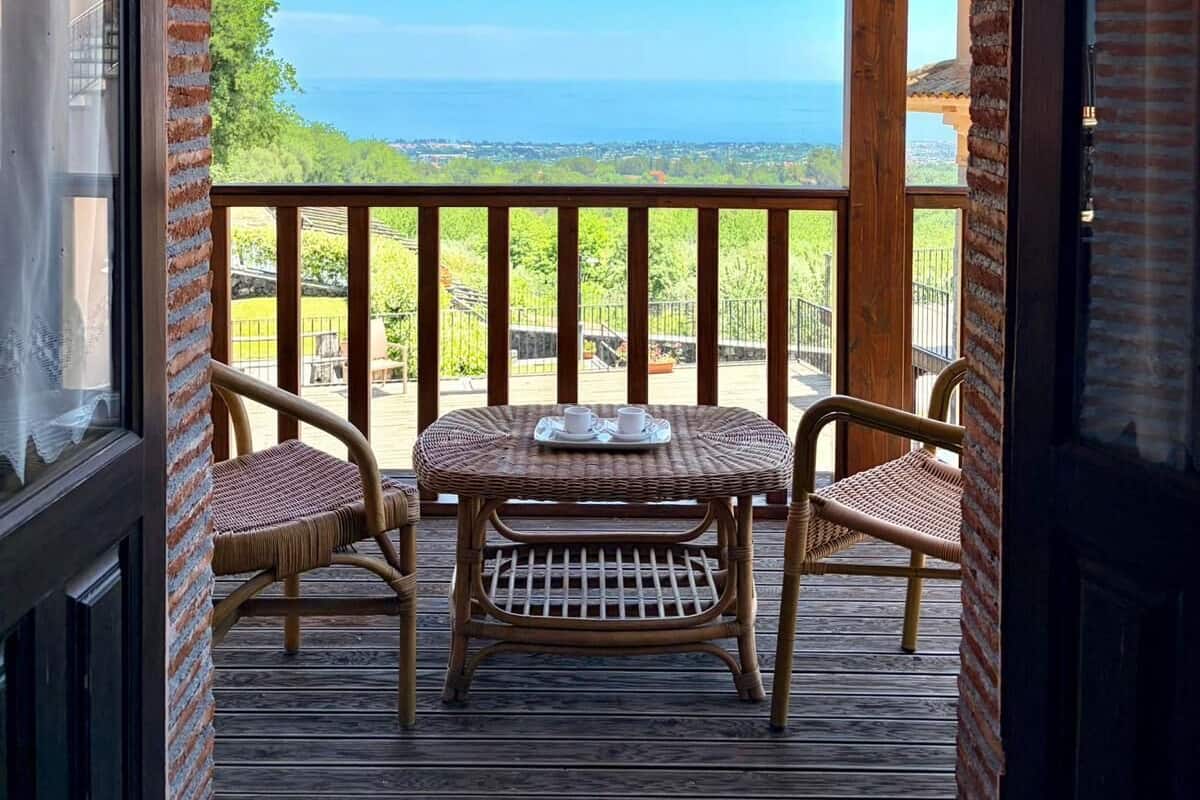 A wooden deck with a table and chairs, overlooking a scenic view.