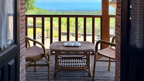 Terraza de madera con mesa y sillas, con vista panorámica.