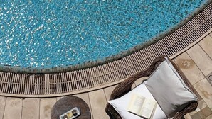 Zona de piscina con una silla de mimbre, un libro y una mesita.