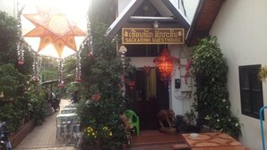 Una casa de huéspedes con un letrero, asientos exteriores y plantas decorativas.