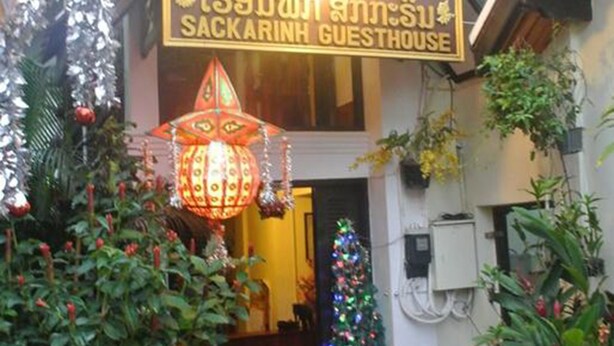 Entrada de una casa de huéspedes con un letrero, un árbol de Navidad y un farol decorativo.