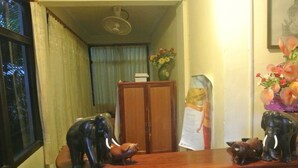 Un mostrador de recepción con paneles de madera, un ventilador en lo alto, un armario de madera y un cartel en la pared.