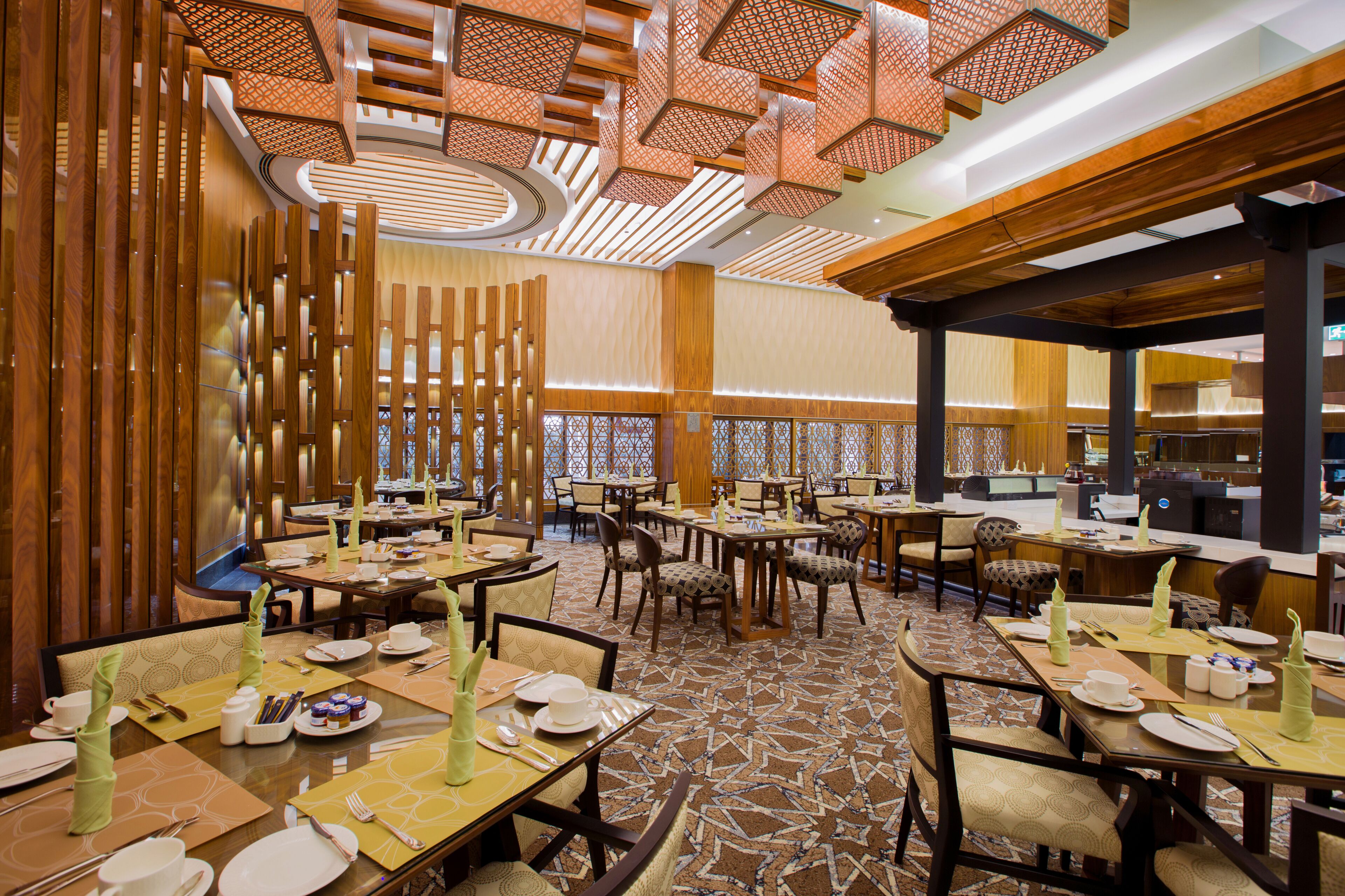 Une salle à manger d’hôtel avec plusieurs tables dressées, des lambris en bois sur les murs et un tapis à motifs.