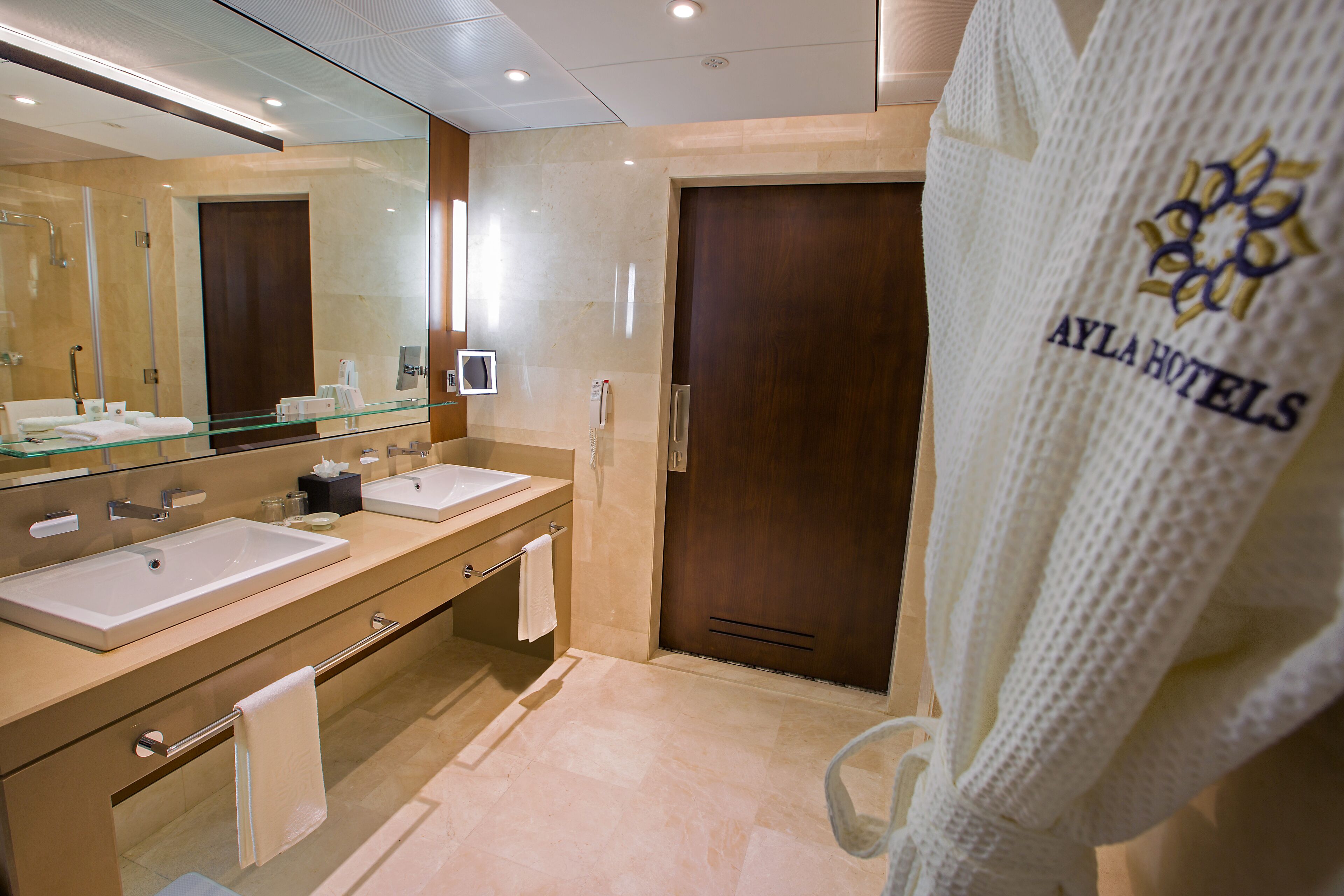 Une salle de bain moderne avec deux lavabos, une douche en verre et une porte en bois.