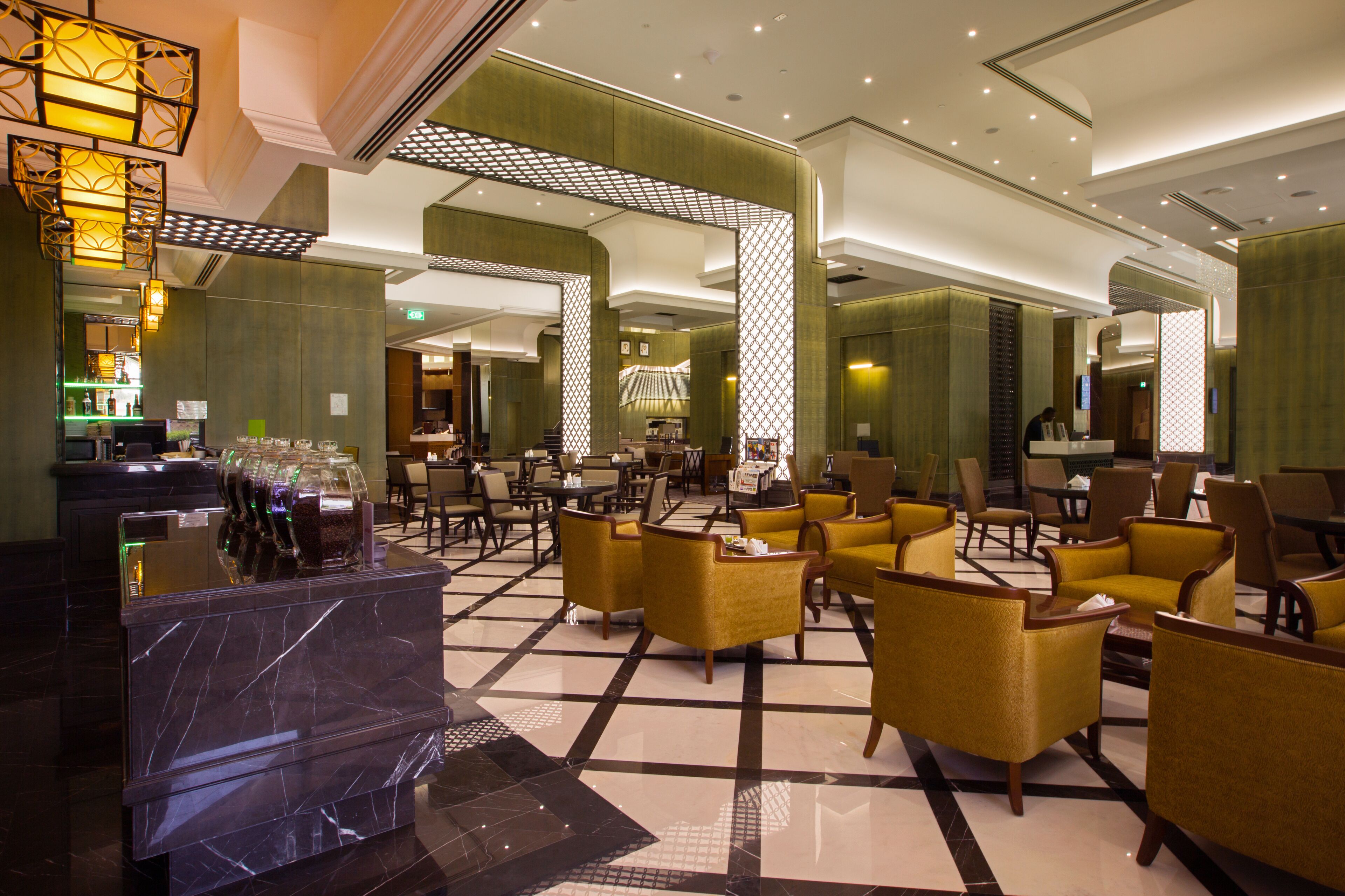 A spacious lobby with a check-in counter, seating area, and a bar.