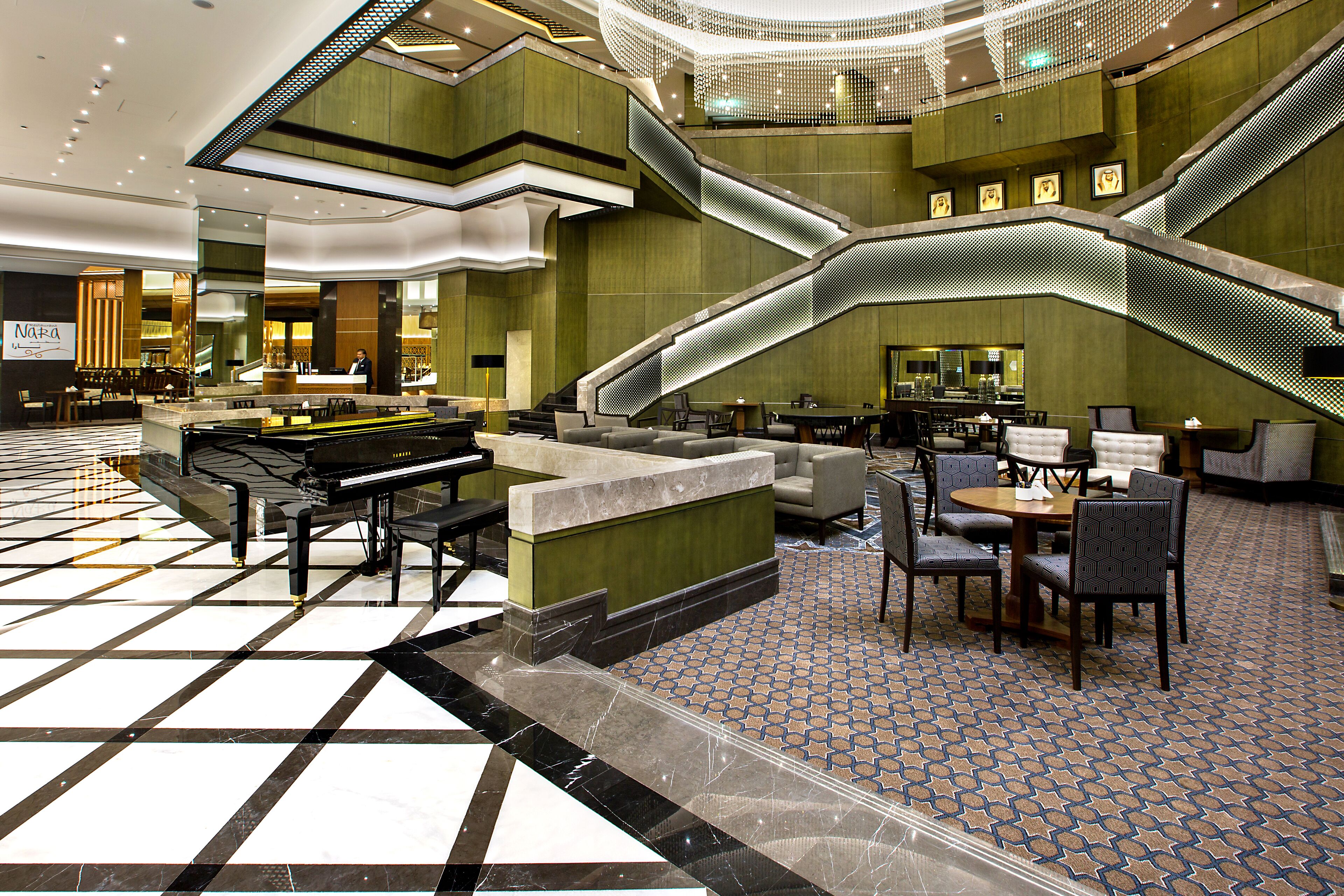 A lobby with a check-in counter, seating area, and a staircase.