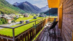 Une cabane en bois dotée d’un balcon donnant sur un village et des montagnes.