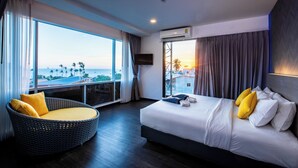 A modern hotel room with a large bed, a comfortable chair, and a view of the cityscape. - Wake Up Aonang Hotel (Krabi)