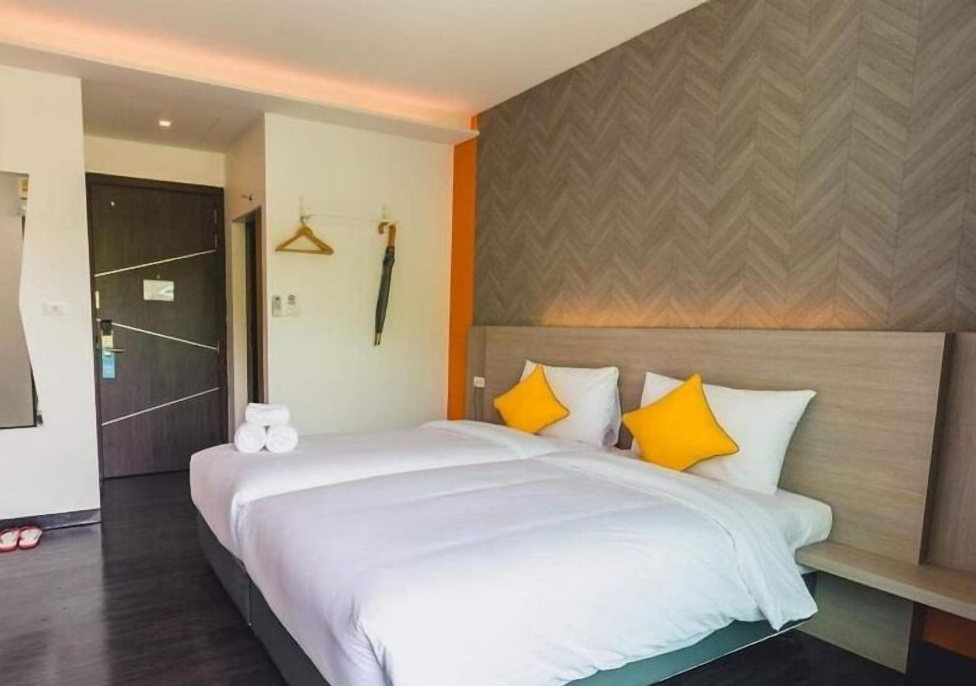 A hotel room with a large bed, a wooden headboard, and a herringbone-patterned wall.