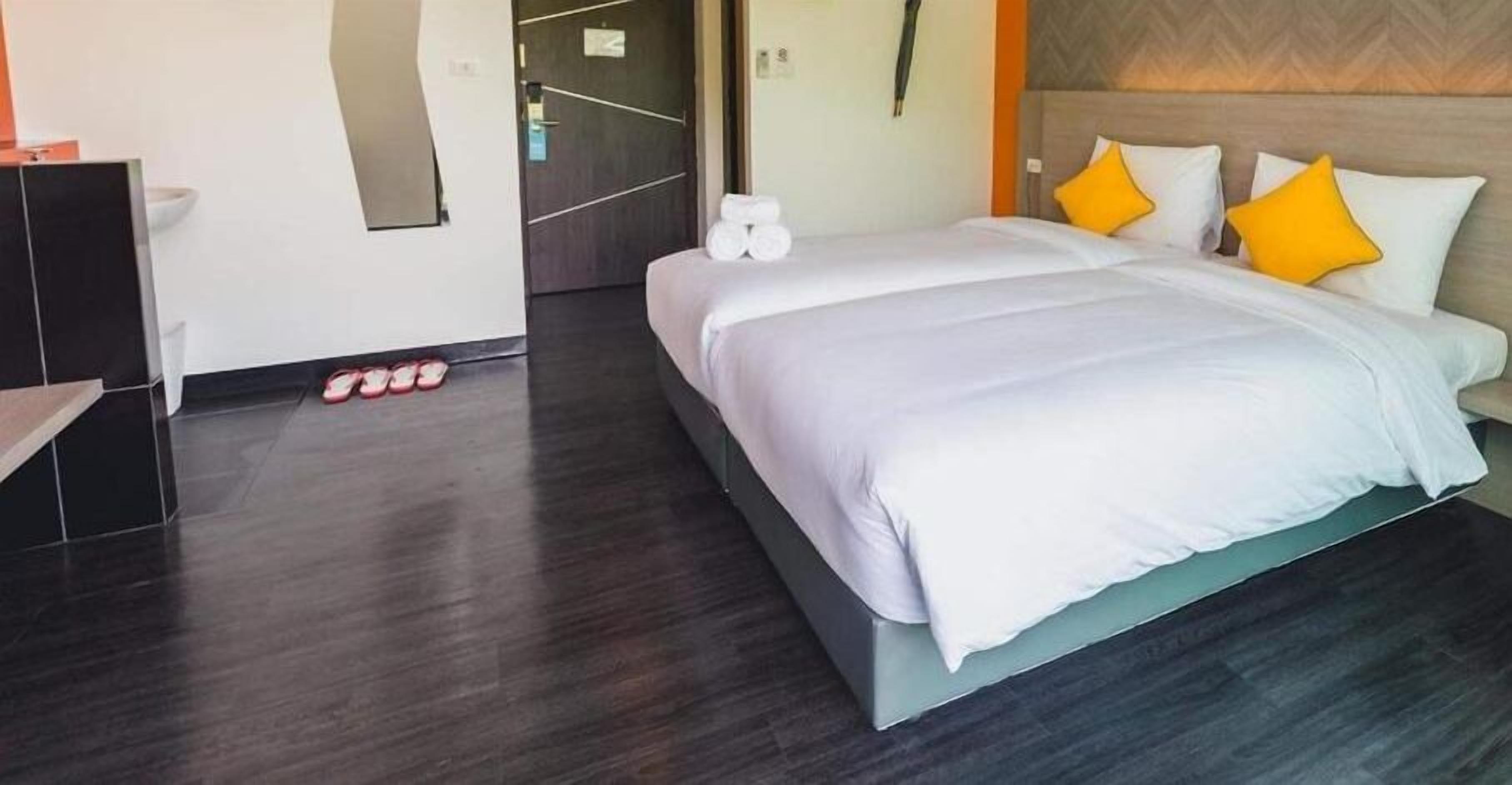 Ein modernes Hotelzimmer mit einem großen Bett, Holzboden und einer Tür zum Badezimmer.