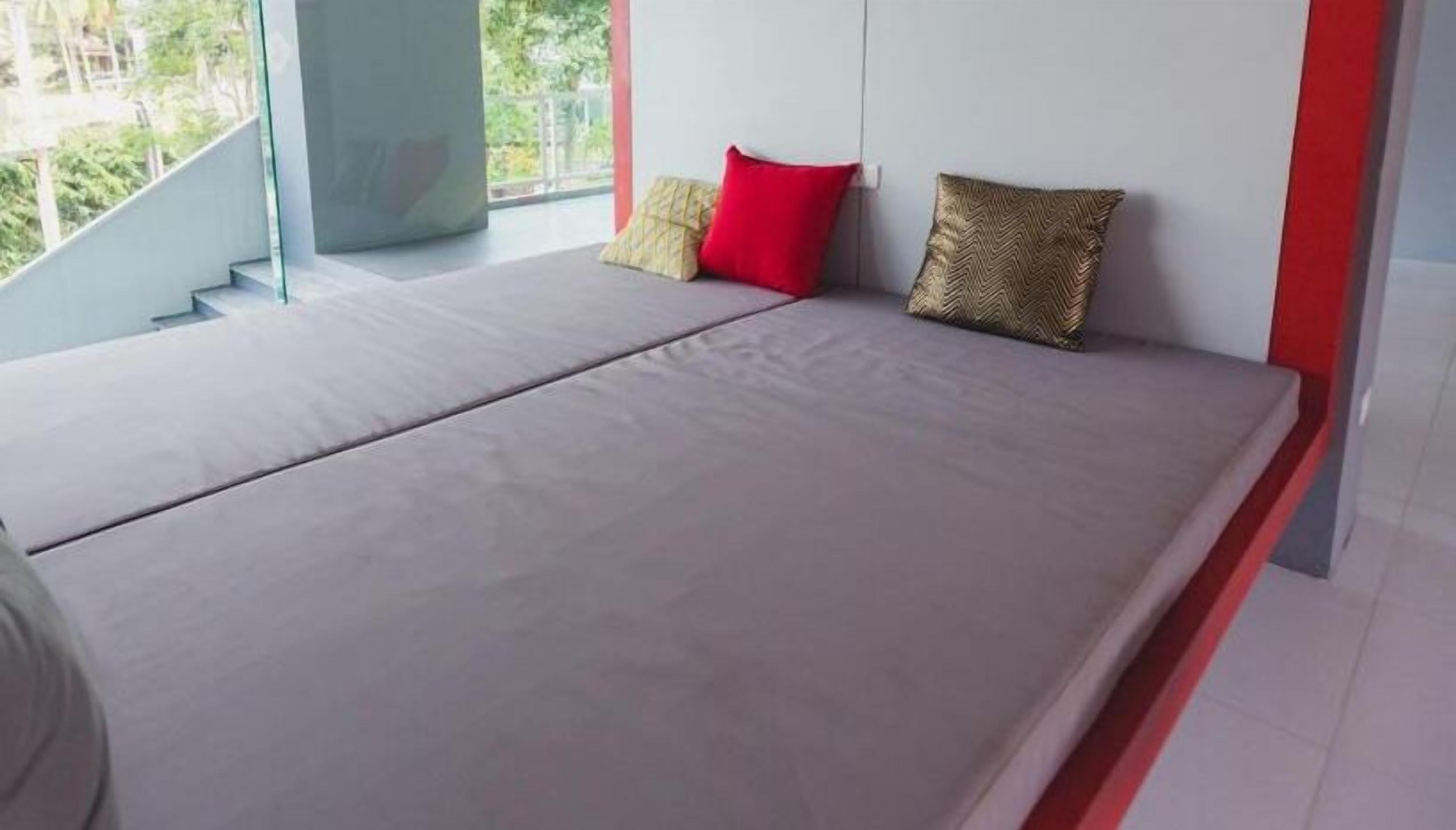 Ein modernes Schlafzimmer mit einem großen Bett, einer Glasstairnase und Blick auf Grünfläche.