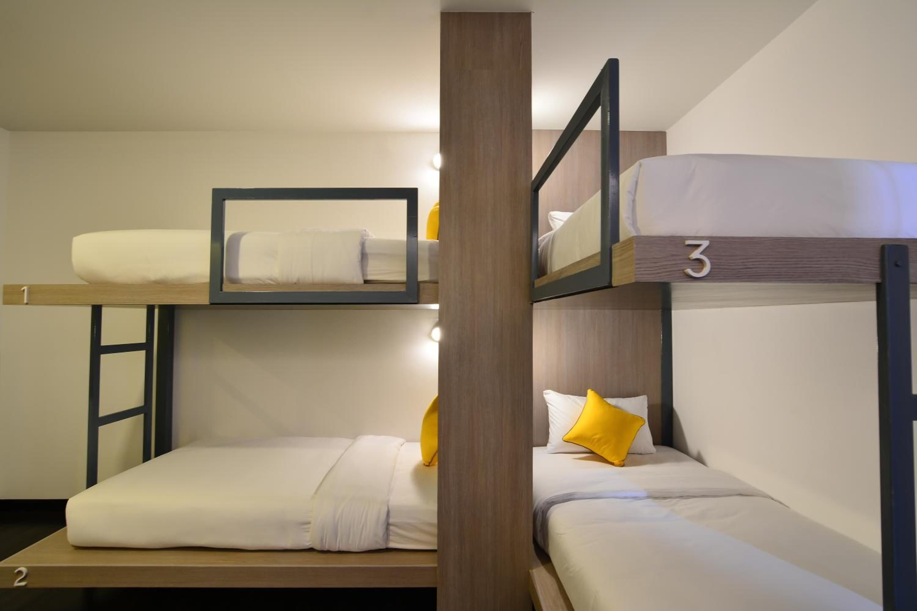 Habitación con literas triples, cada una con colchón y almohadas.