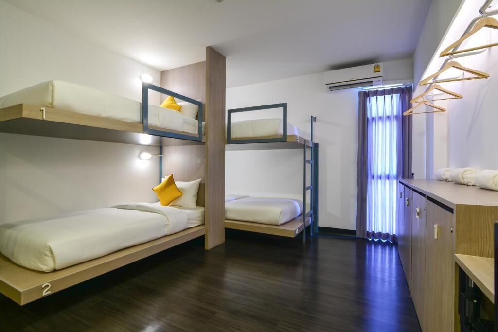A compact room with bunk beds, a small kitchenette, and a window with curtains.