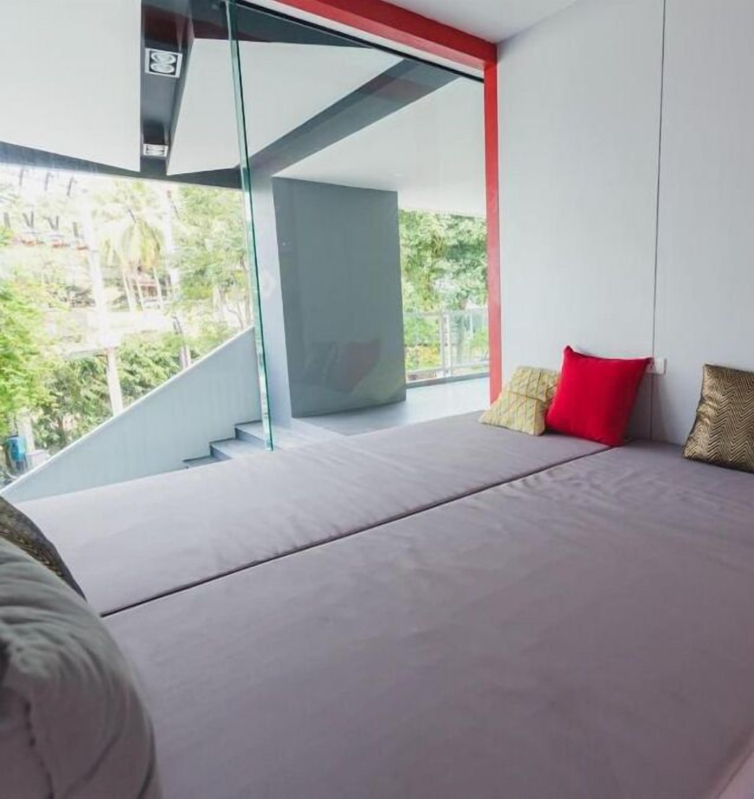 Ein modernes Schlafzimmer mit einem großen Bett, einer Glastreppe und Blick auf Grünfläche.
