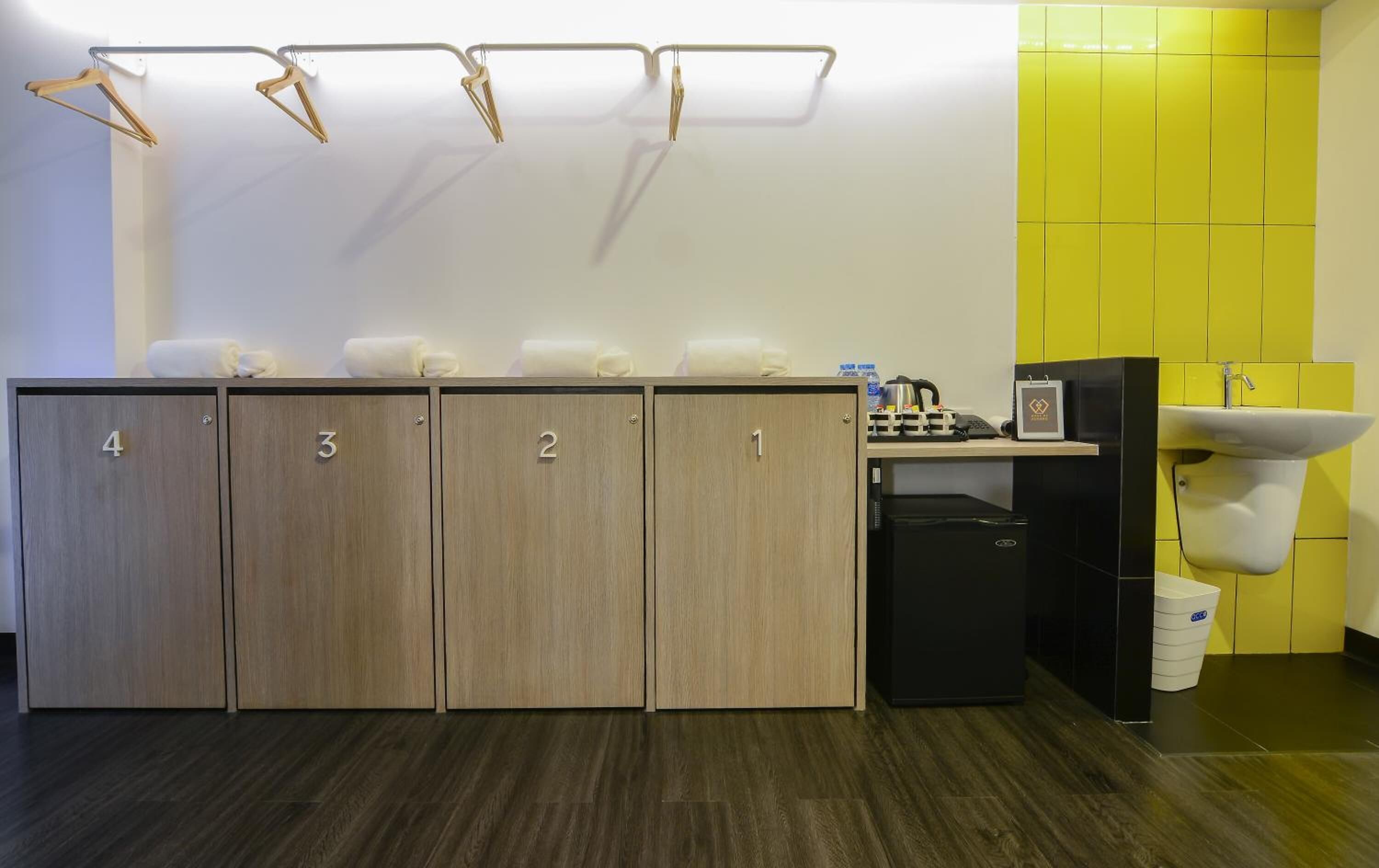 A modern bathroom with wooden lockers numbered 1 to 4, a sink, and a mirror.