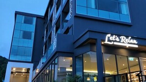 A modern hotel building with a prominent 'Let's Relax' sign. - Wake Up Aonang Hotel (Krabi)