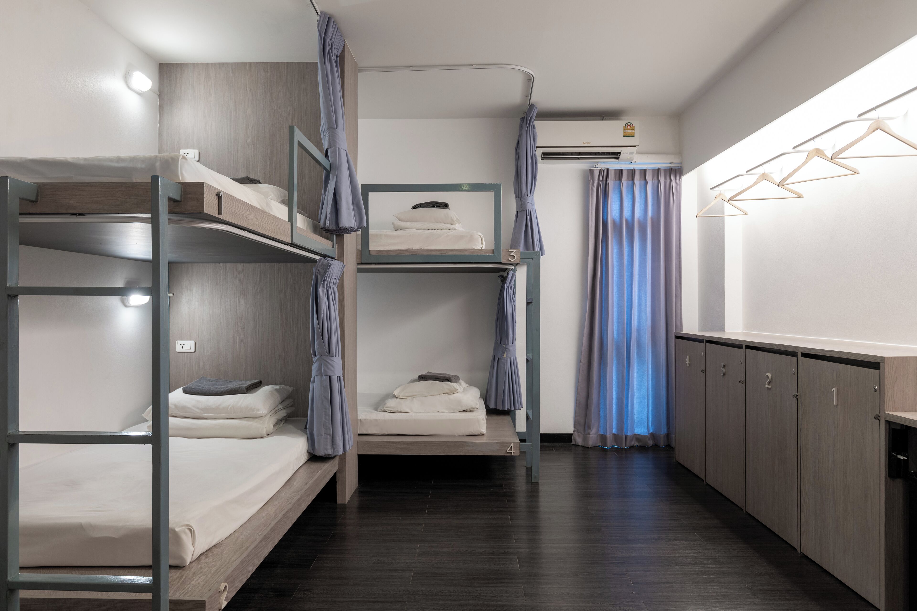 A bunk bed room with a kitchenette, a window with curtains, and a wardrobe.