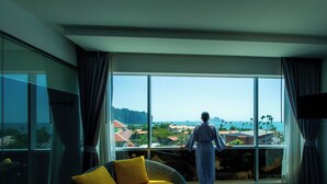 A room with a large window, a bed, a chair, and a flat-screen TV. - Wake Up Aonang Hotel (Krabi)