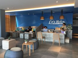 Een moderne spa-ontvangstzone met een blauwe accentmuur, comfortabele zitplaatsen en een receptiebalie.