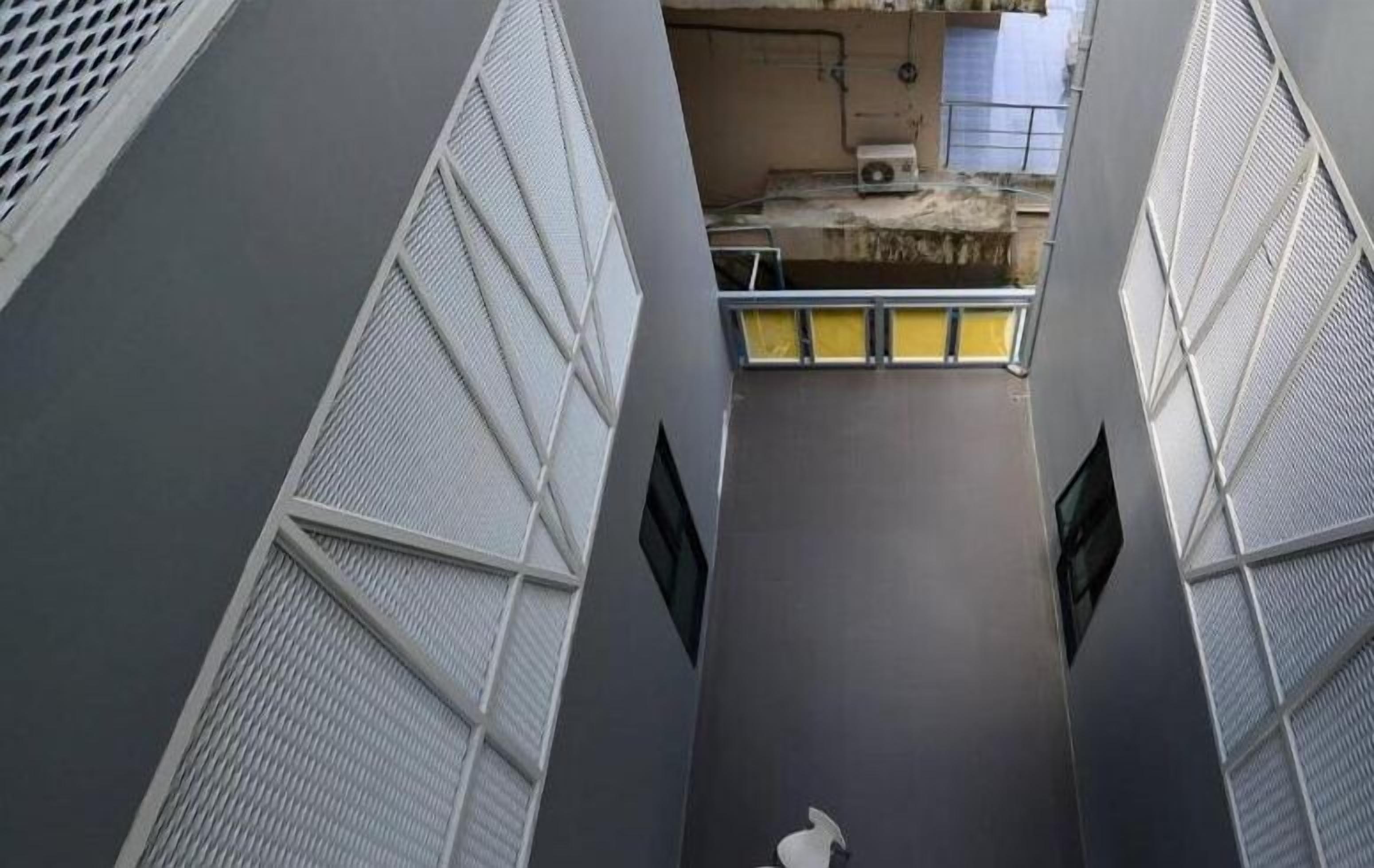 A narrow, enclosed corridor with metal mesh walls and a central walkway.