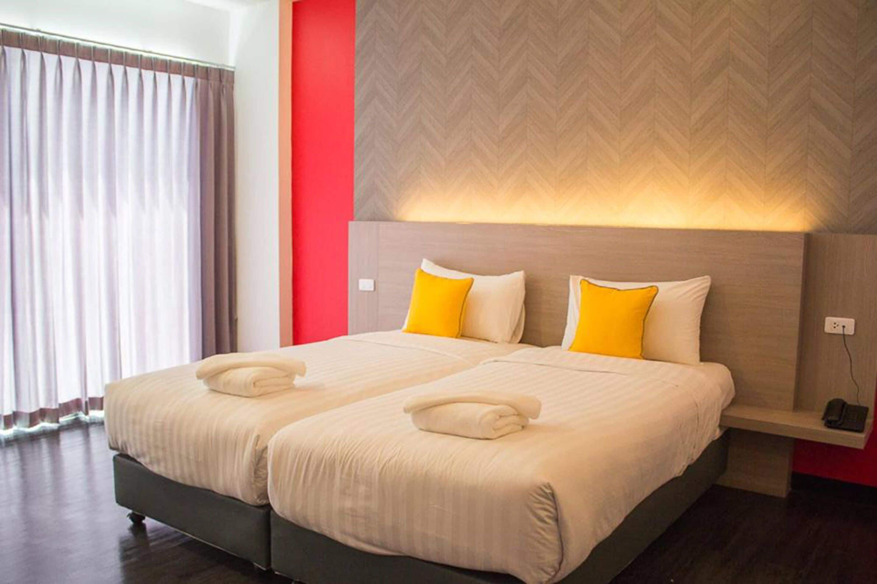 A double bed with two pillows, a bedside table, and a wall-mounted light fixture.