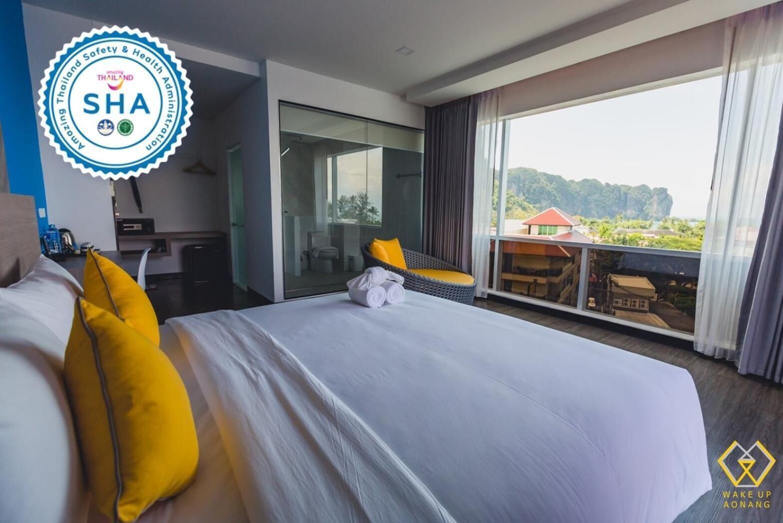 Habitación de hotel moderna con una cama grande, cabina de ducha de vidrio y un balcón con vistas al paisaje.