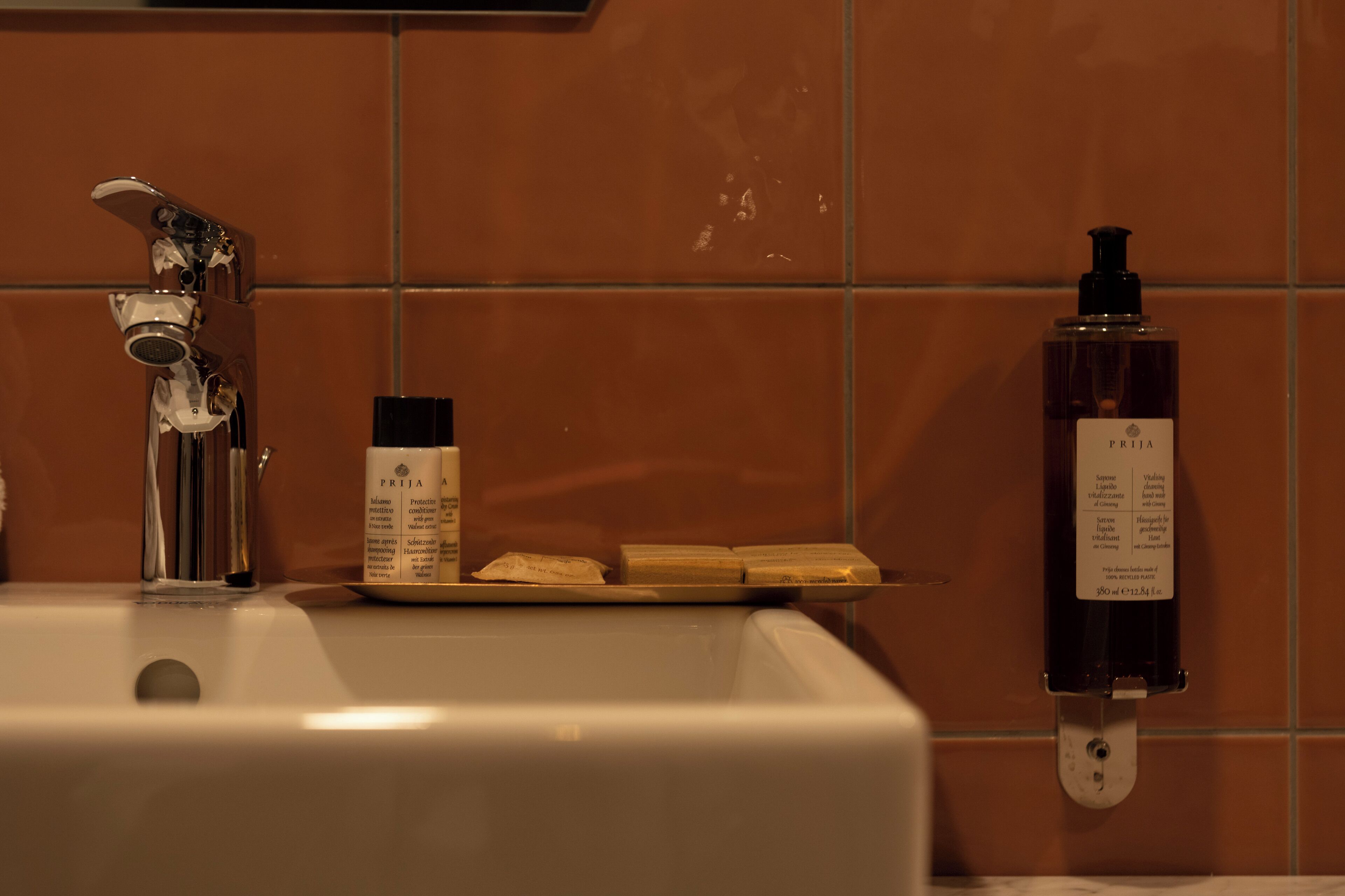 Un lavabo de salle de bain avec un robinet, un distributeur de savon et un porte-savon contenant deux pains de savon.