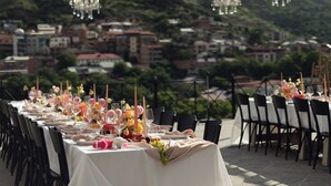 A long table set for a formal outdoor event with a cityscape view in the background. - Margot Old Tbilisi (Tbilisi)