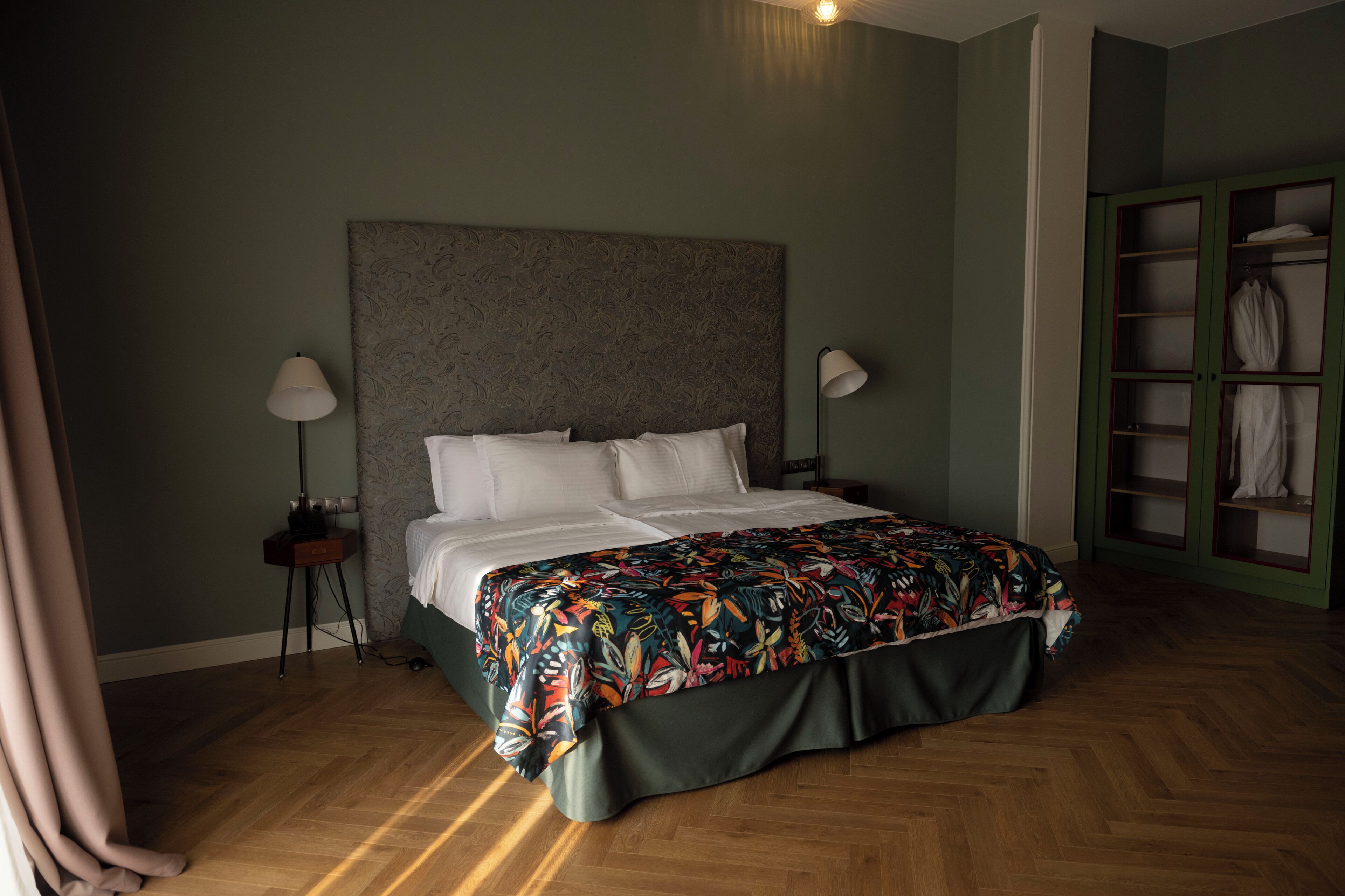 A bedroom with a bed, a nightstand, a lamp, and a wardrobe.