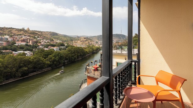 A balcony with a view of a river, a cityscape, and a table with chairs. - Margot Old Tbilisi (Tbilisi)