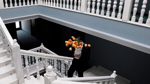 A grand staircase with white balustrades and a vase of orange flowers. - Margot Old Tbilisi (Tbilisi)