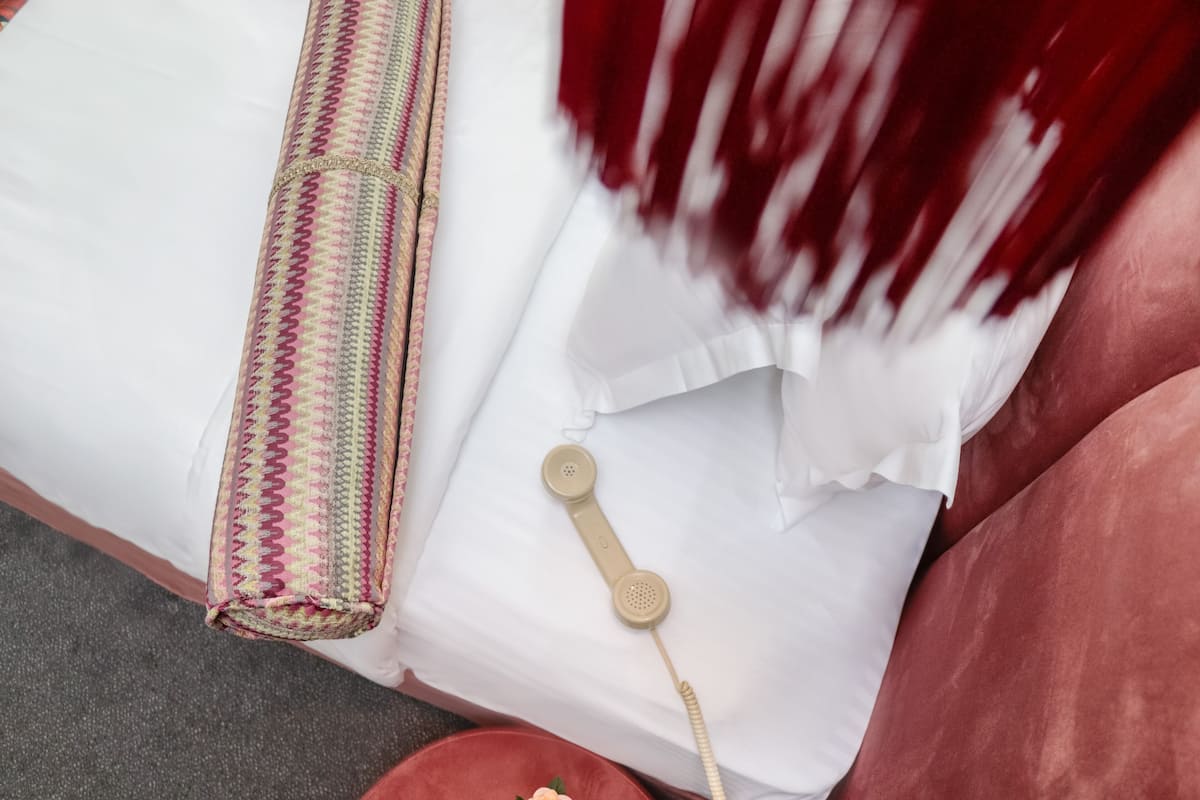 A bed with a patterned blanket, a white pillow, and a beige telephone.