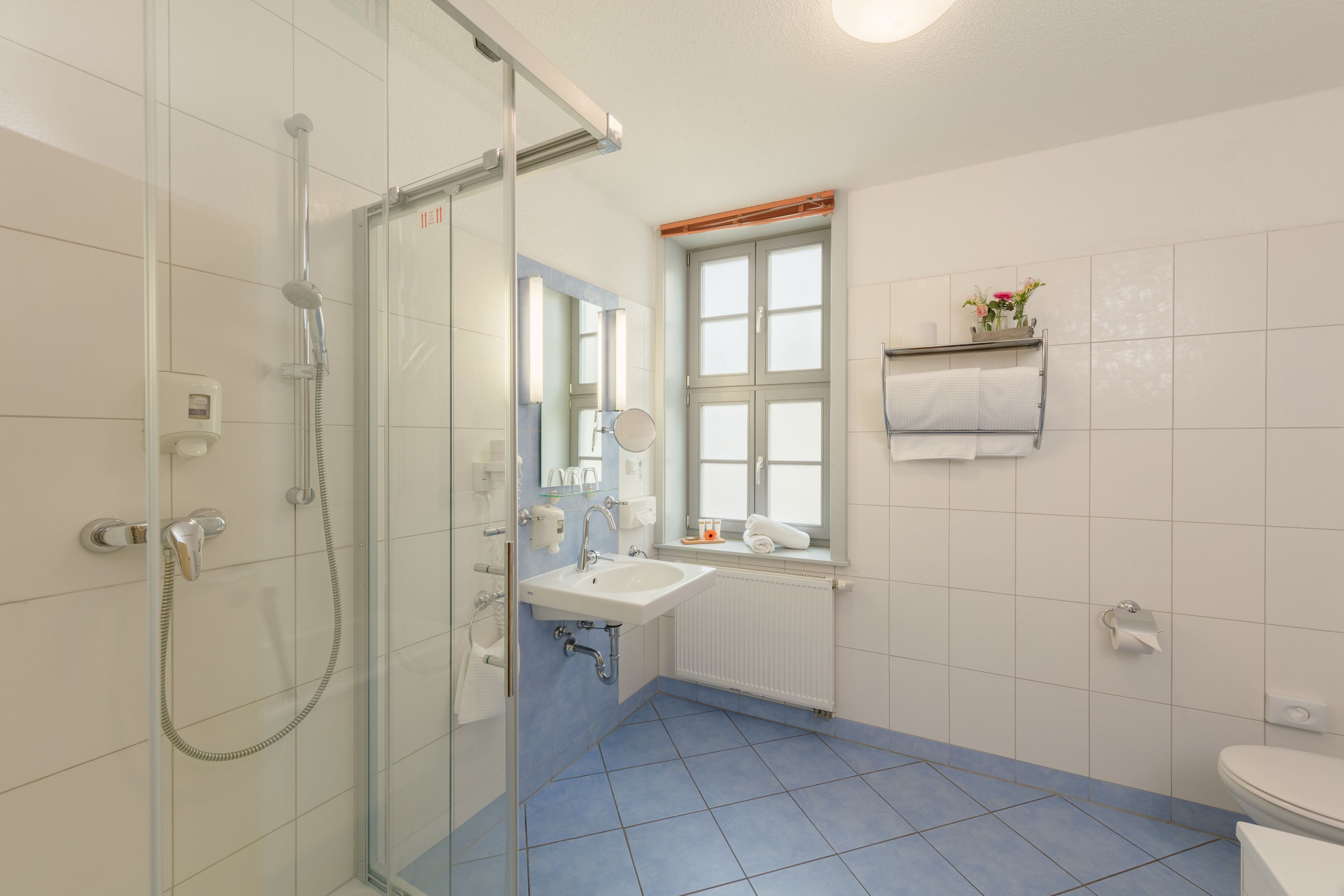 Une salle de bain avec une douche à parois de verre, un lavabo, des toilettes et une fenêtre donnant sur un beau paysage.