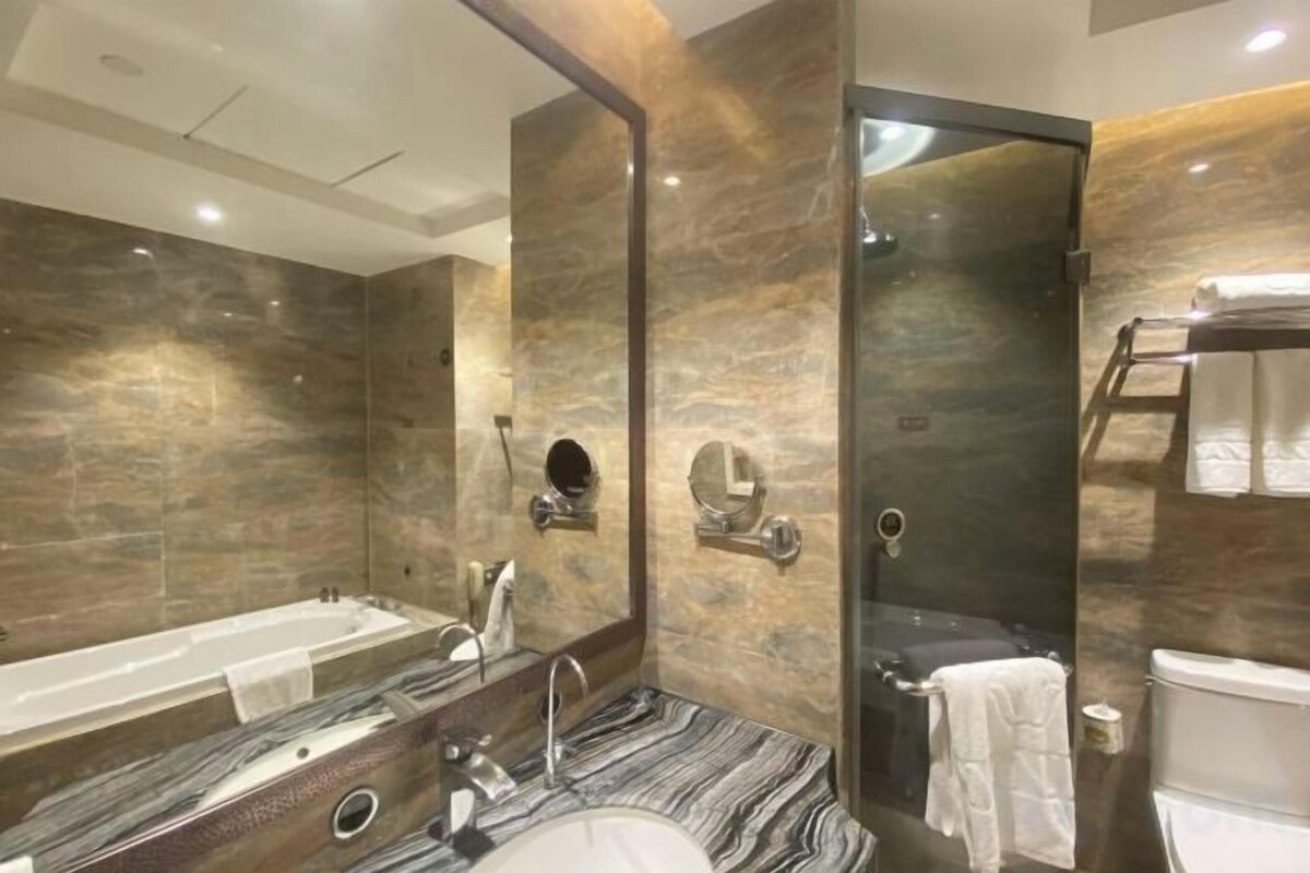 Un baño moderno con tocador de mármol, bañera, ducha y retrete.