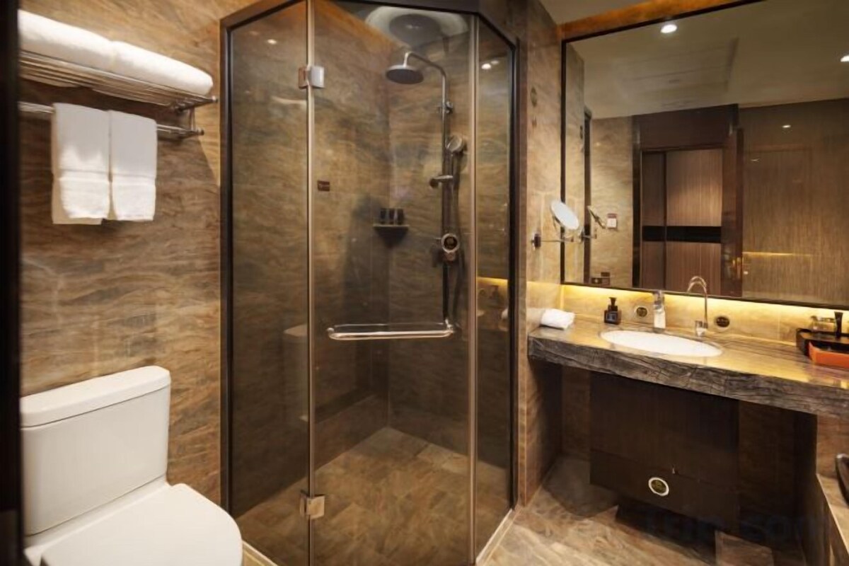 A modern bathroom with a glass-enclosed shower, a marble countertop sink, and a large mirror.