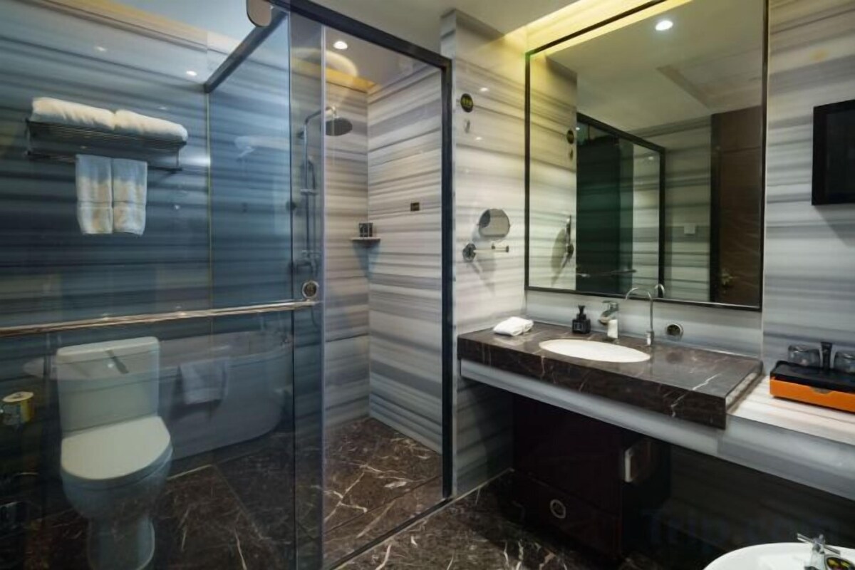 A modern bathroom with a glass-enclosed shower, a marble-topped sink, and a large mirror.