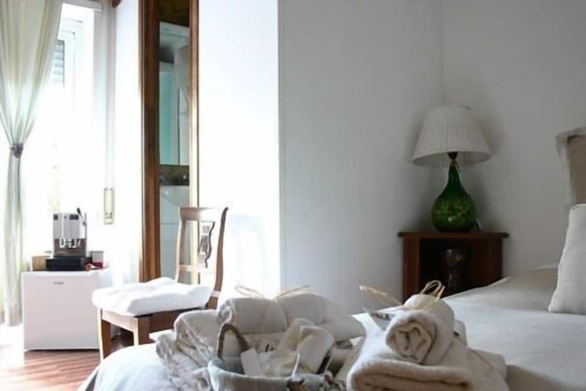 Une chambre d’hôtel avec un lit, une chaise, une lampe et un panier rempli de serviettes.