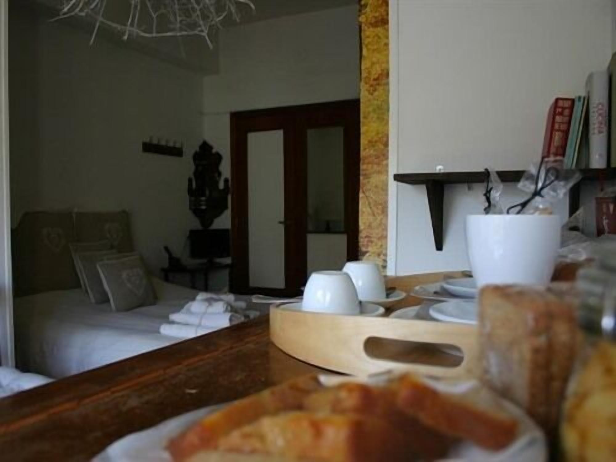 A room with a bed, a wooden table with cups and a tray, and a mirror on the wall.