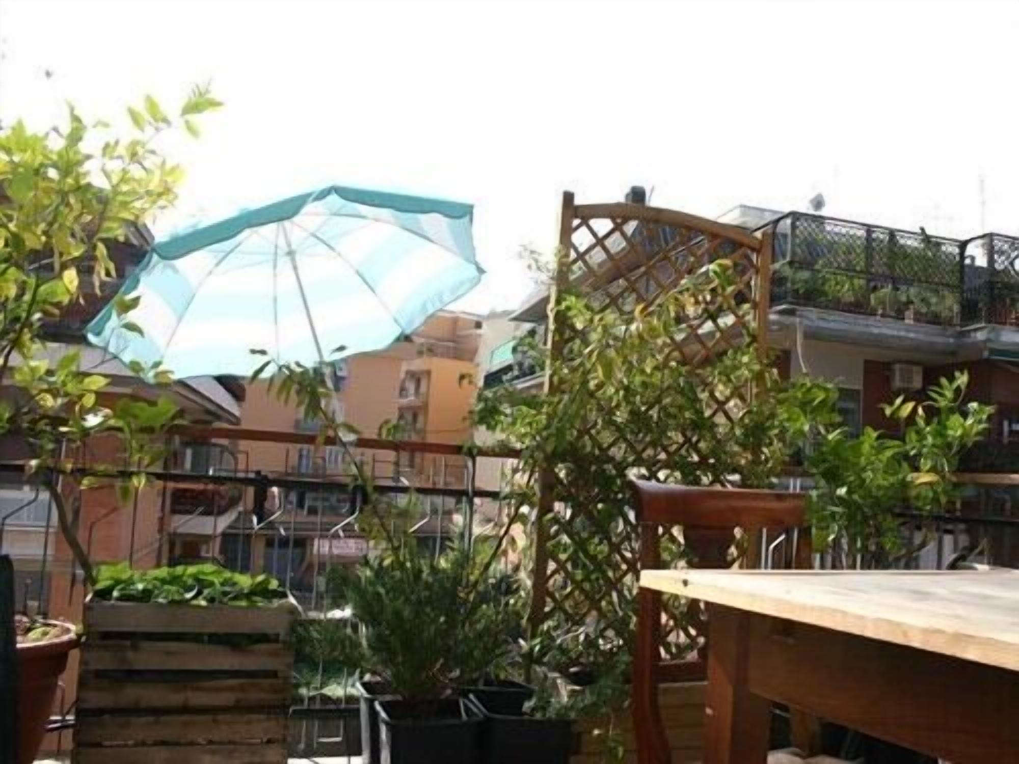 A patio area with a wooden table, potted plants, and a blue umbrella.
