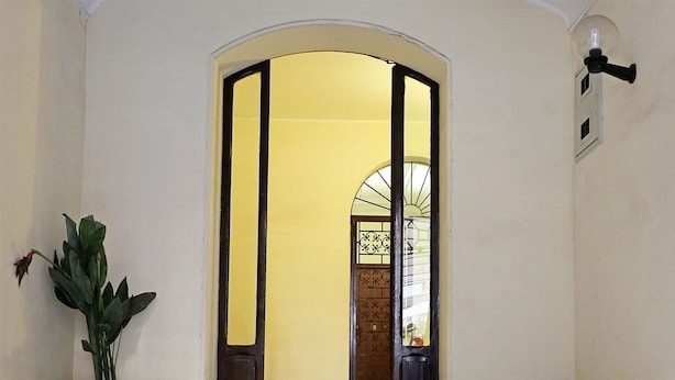 A staircase leading to a room with a yellow wall and a wooden door. - AdoraSuite B&B (Rome)