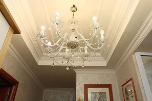 Un gran candelabro con múltiples brazos y adornos de cristal en una habitación con paredes blancas y un marco de puerta de madera.